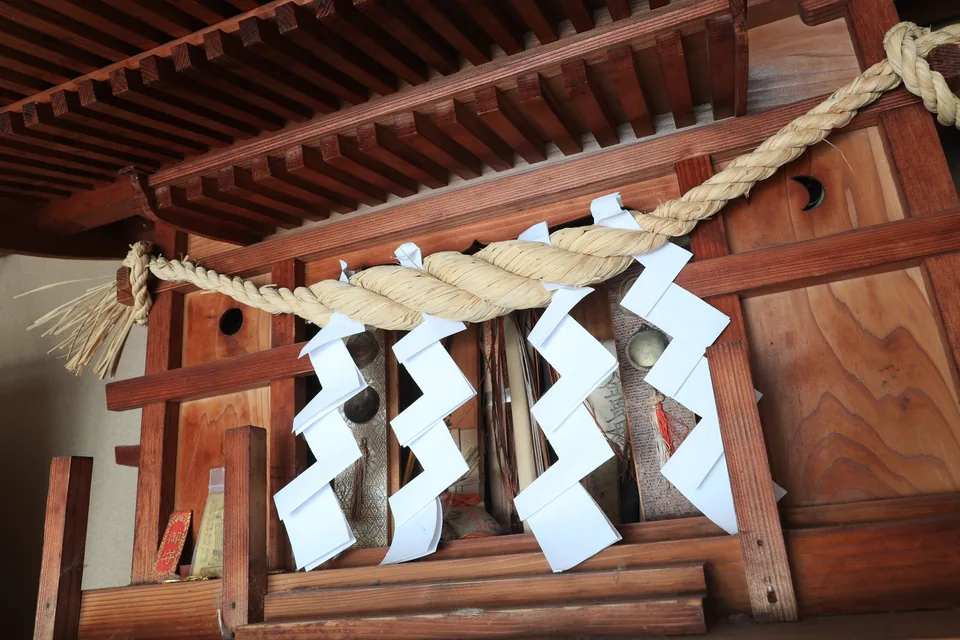木製の宮形と白い神具を棚板に整えた家庭の神棚