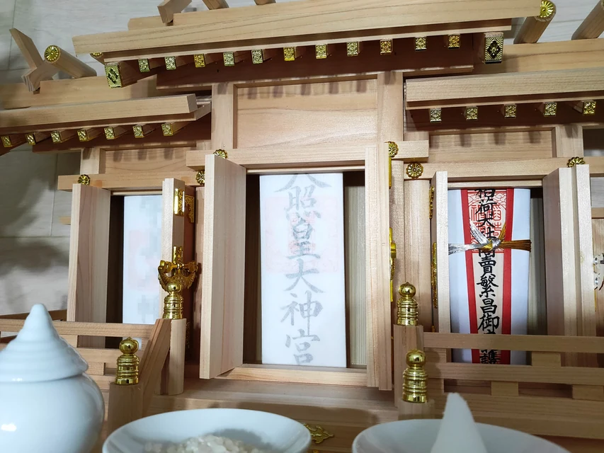 家庭の神棚に神宮大麻と氏神神社のお神札を丁寧に納める様子