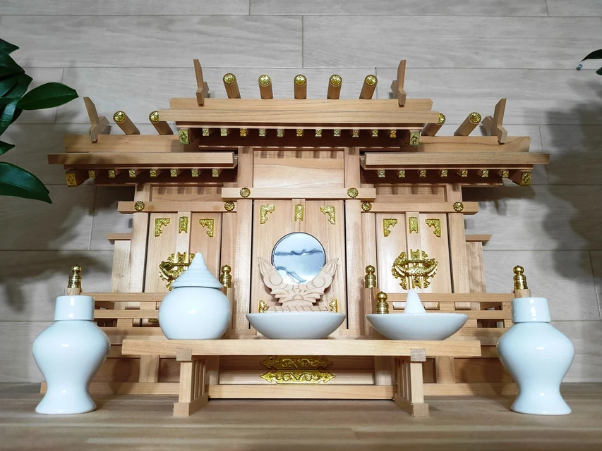 神棚の宮形へお神札を丁寧に納める手元