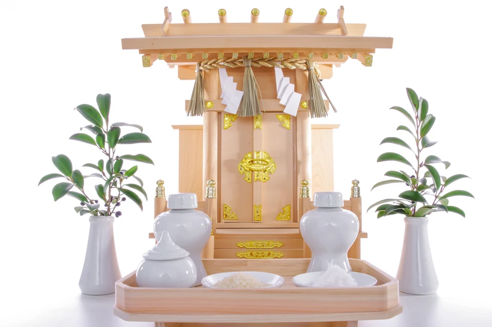 神棚から傷んだお供えを静かに下げて器を整える様子